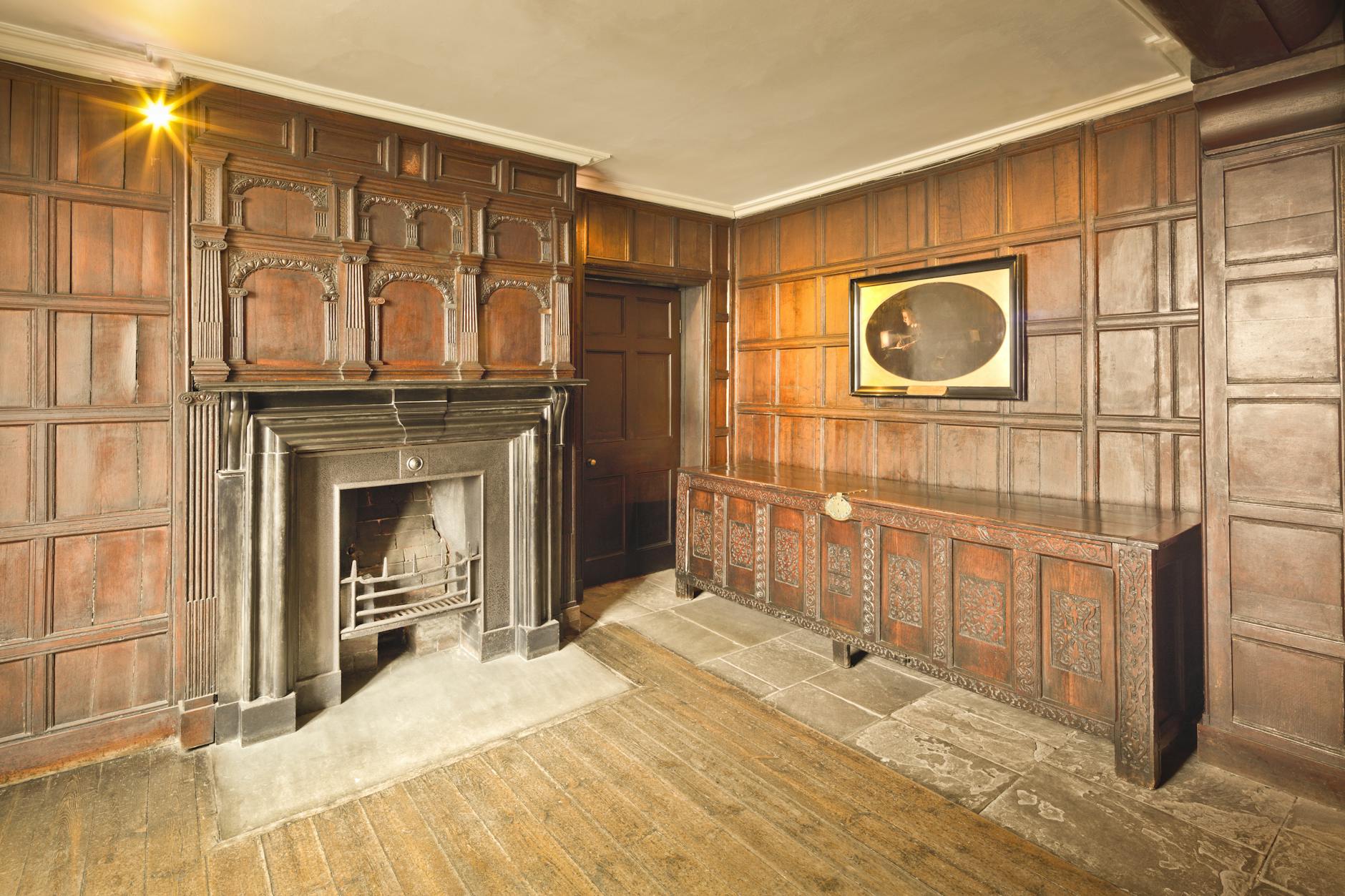 Elegant historical room with wooden paneled walls and traditional fireplace in England.