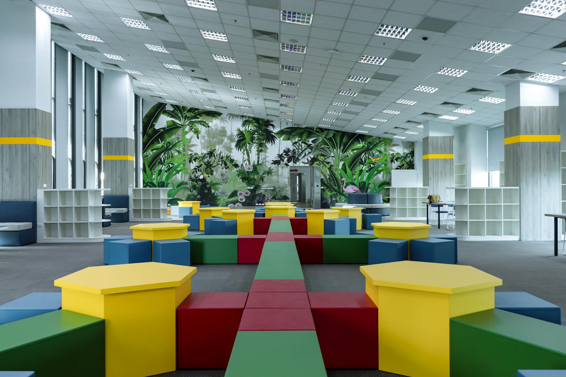 Vibrant indoor playground featuring colorful geometric shapes and nature-themed murals.