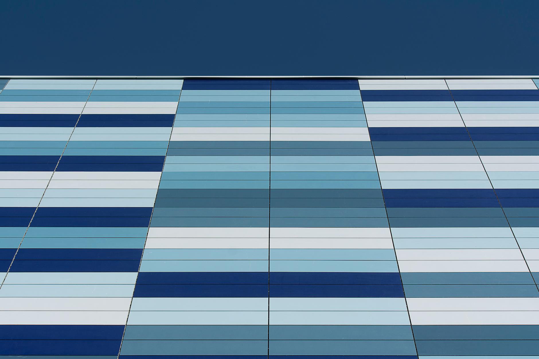 Close-up of a modern building facade with blue geometric patterns and stripes.