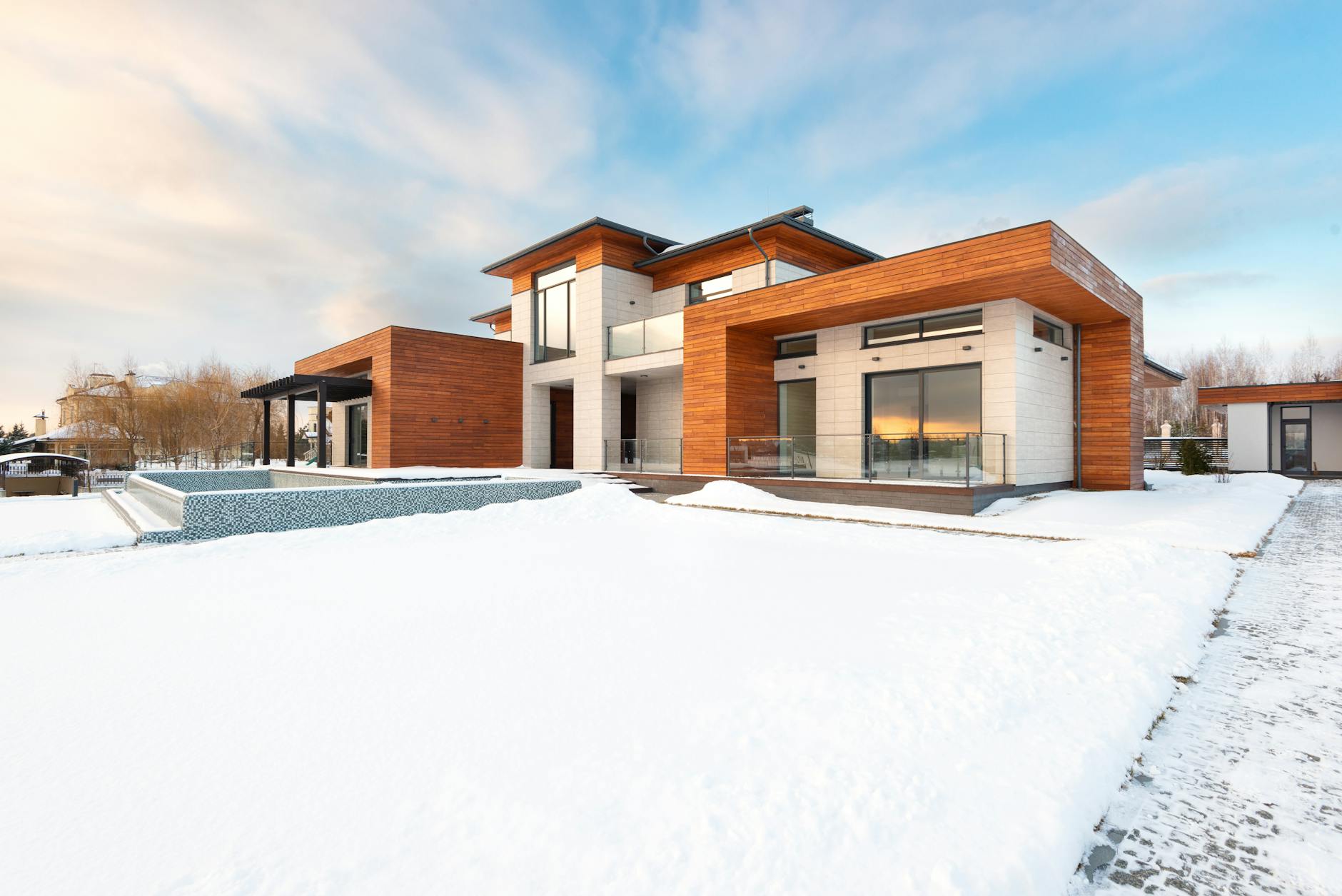 Spacious suburban cottage house with modern architecture design with stone and wooden panels and large private yard in winter countryside