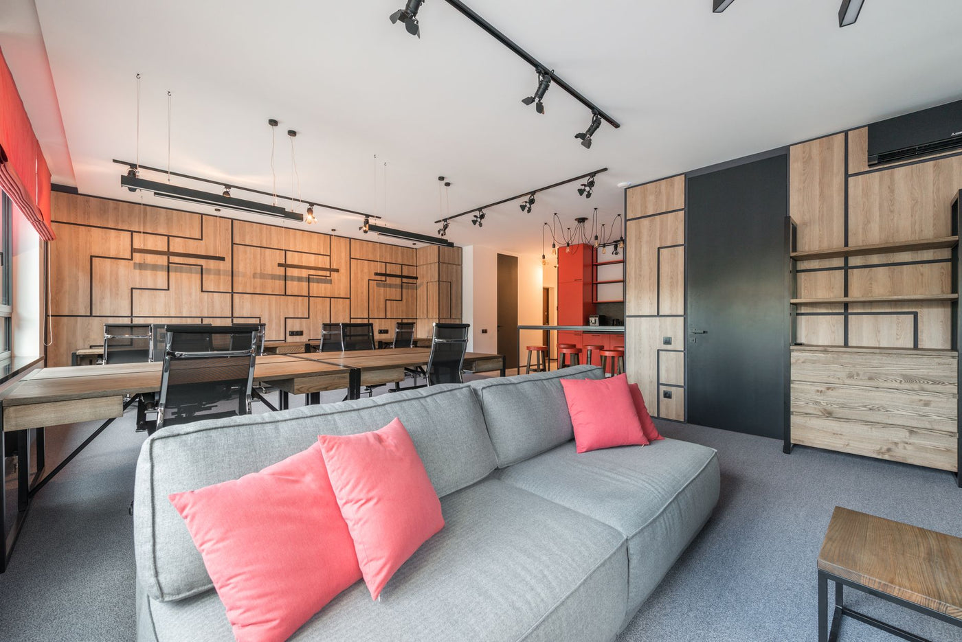 Creative design of workspace with couch between tables and armchairs under ceiling with hanging lamps in daytime