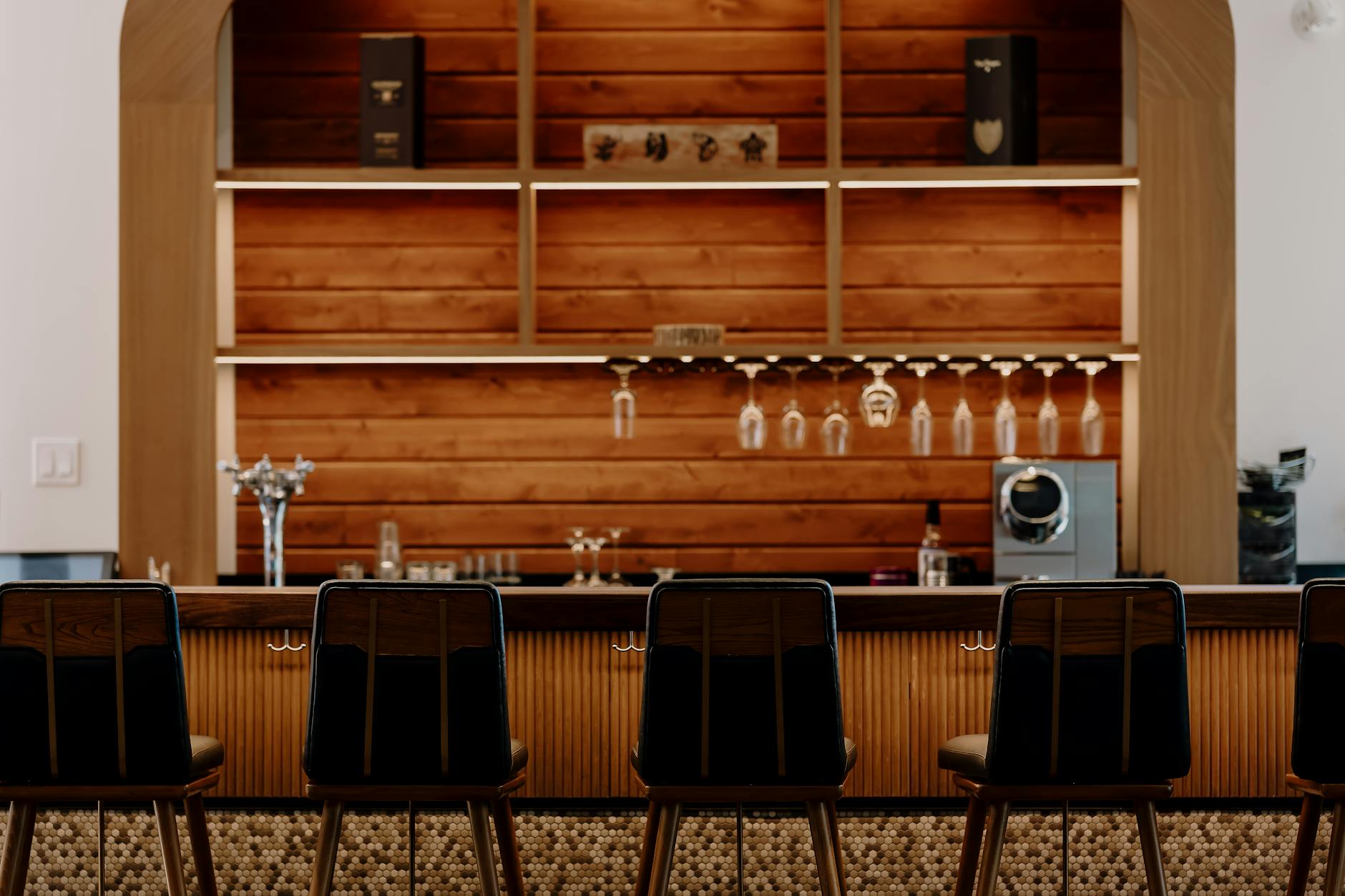 Contemporary bar setting with wooden decor and sleek high chairs.