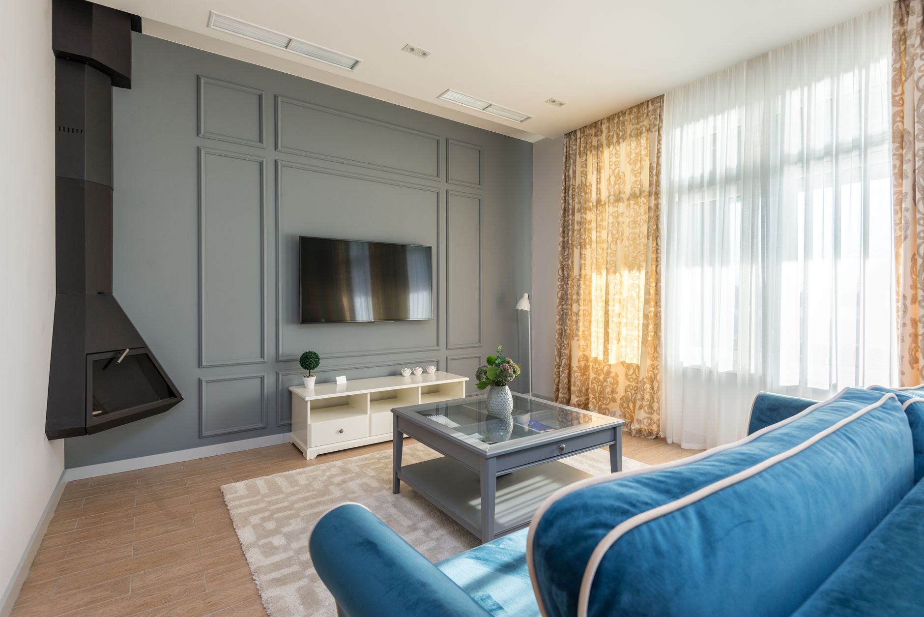 Bright and modern living room with blue couch, fireplace, and natural light.