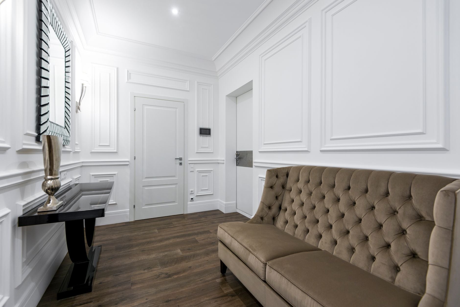 A sophisticated interior with a tufted sofa and a decorative mirror, highlighting classic design elements.