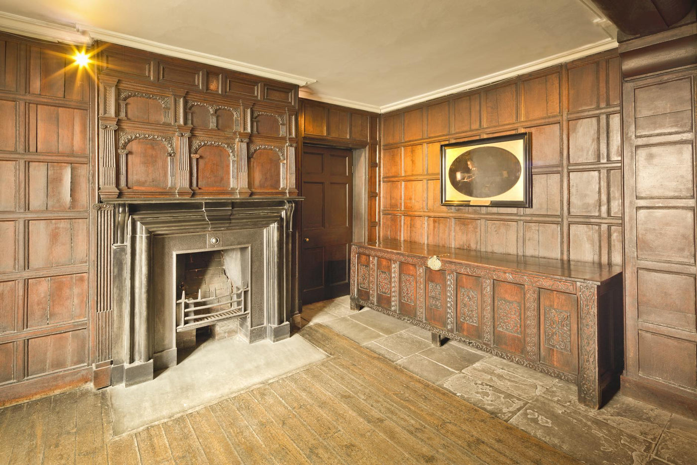 Elegant historical room with wooden paneled walls and traditional fireplace in England.