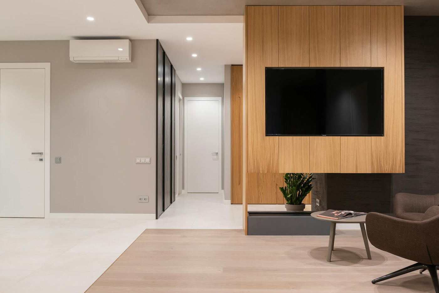 Apartment interior with armchairs and table next to TV on wall and door