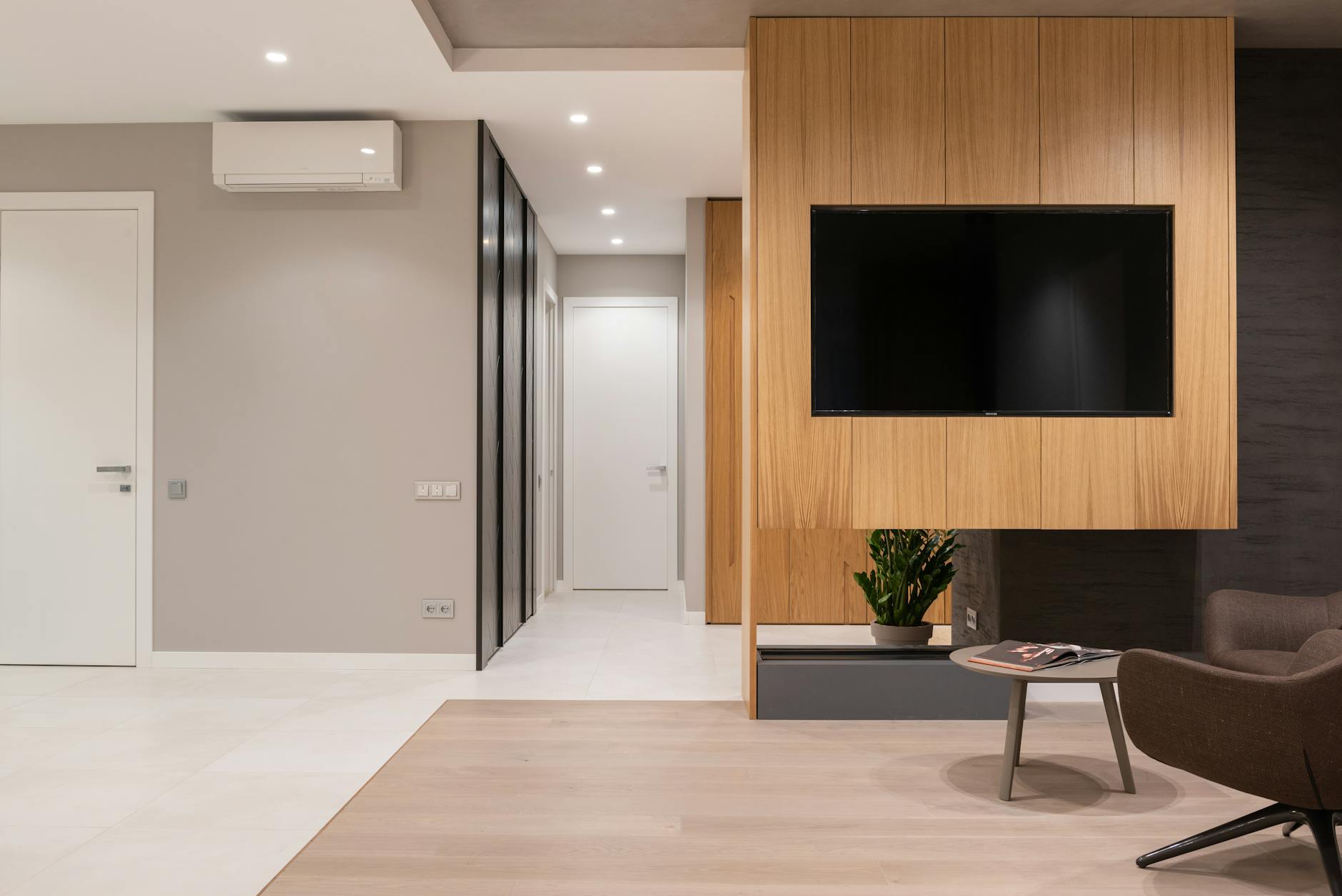 Apartment interior with armchairs and table next to TV on wall and door