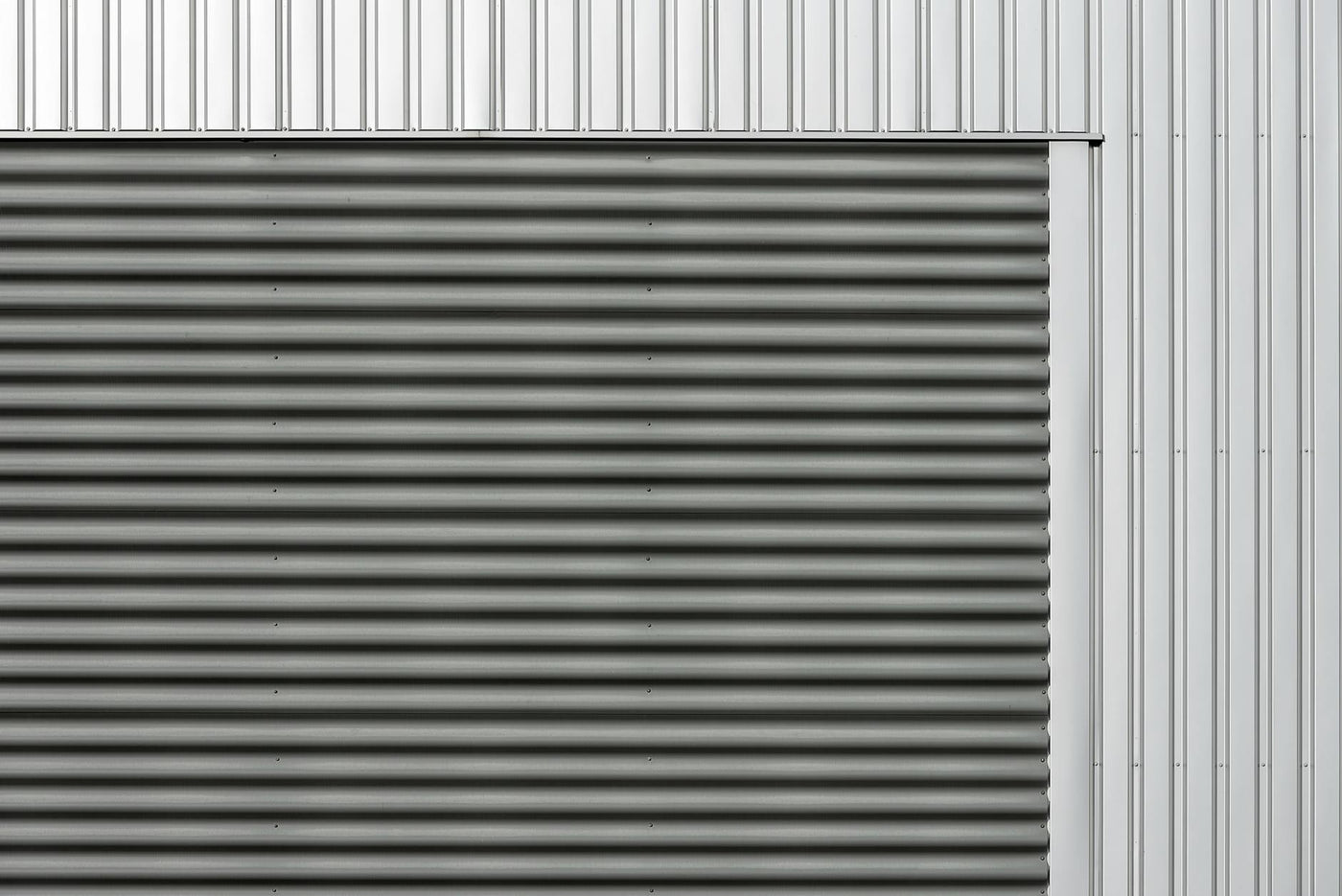 Minimalist metal facade featuring corrugated and smooth vertical panels in gray and silver tones.
