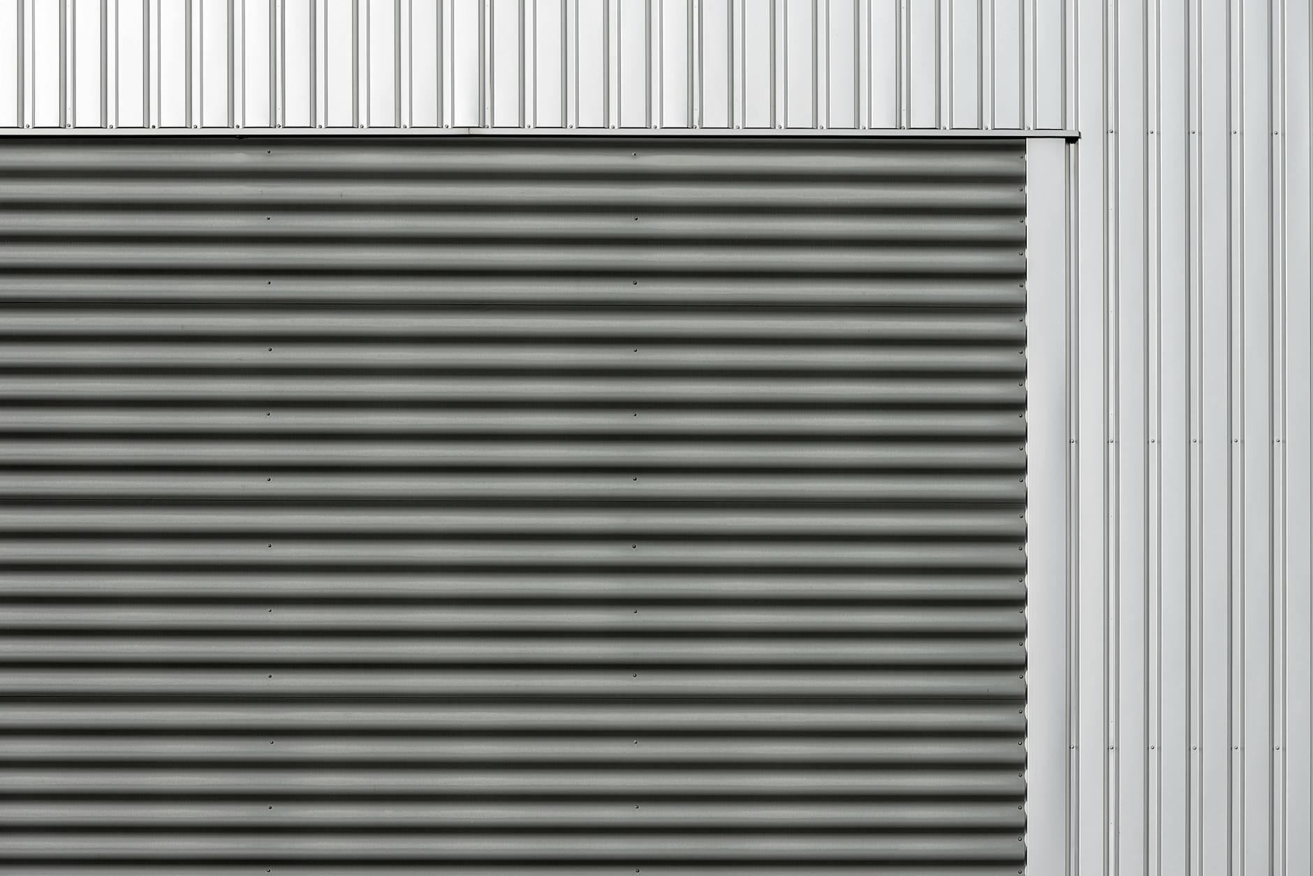 Minimalist metal facade featuring corrugated and smooth vertical panels in gray and silver tones.