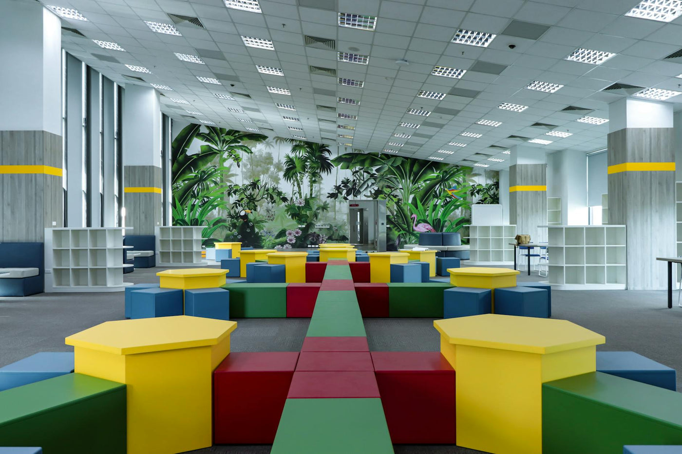 Vibrant indoor playground featuring colorful geometric shapes and nature-themed murals.